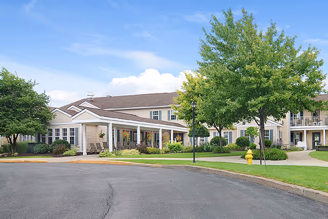 Front exterior of Brookdale Summerfield showing a covered entrance, circular driveway, landscaped lawns and trees under a blue sky.