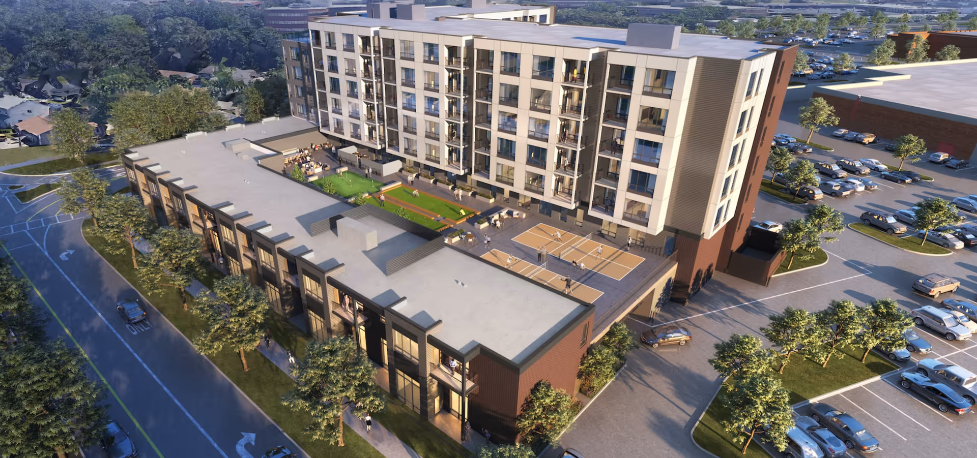 Aerial view of a modern multi-story senior living facility named Aviva Pembroke, featuring outdoor recreational areas including bocce ball courts and a basketball court. The building is surrounded by parking lots, trees, and nearby residential houses.