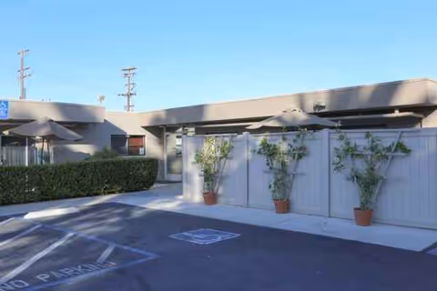 Exterior view of a modern senior care facility with parking and planters.