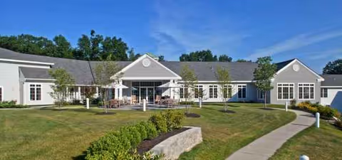 Exterior view of Arbor Ridge at Brookmeade showing lawn, path, and outdoor seating.