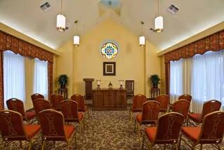 A small chapel style meeting room with rows of red chairs and an altar.