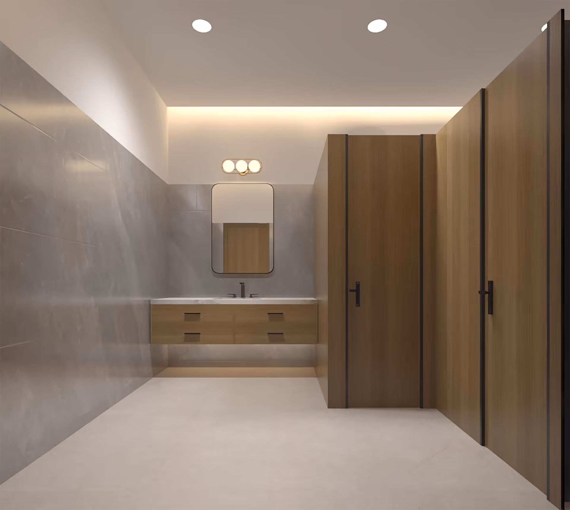 Modern public restroom with light gray tiled walls and floor, featuring a floating wooden vanity with a white countertop and a rectangular mirror above it. To the right, there are wooden stall doors with black handles. The ceiling has recessed lighting and a wall-mounted light fixture above the mirror.