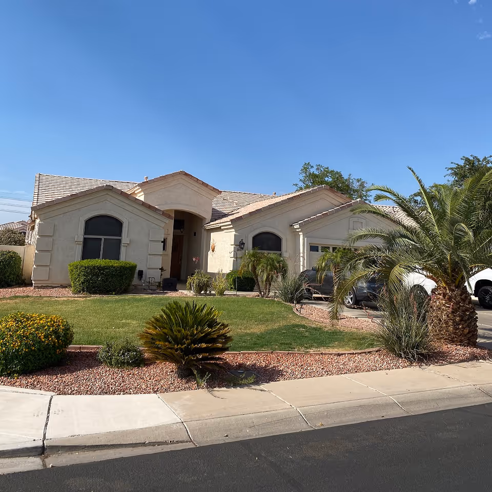 Single-story suburban house with arched windows, landscaped front yard, and parked cars.