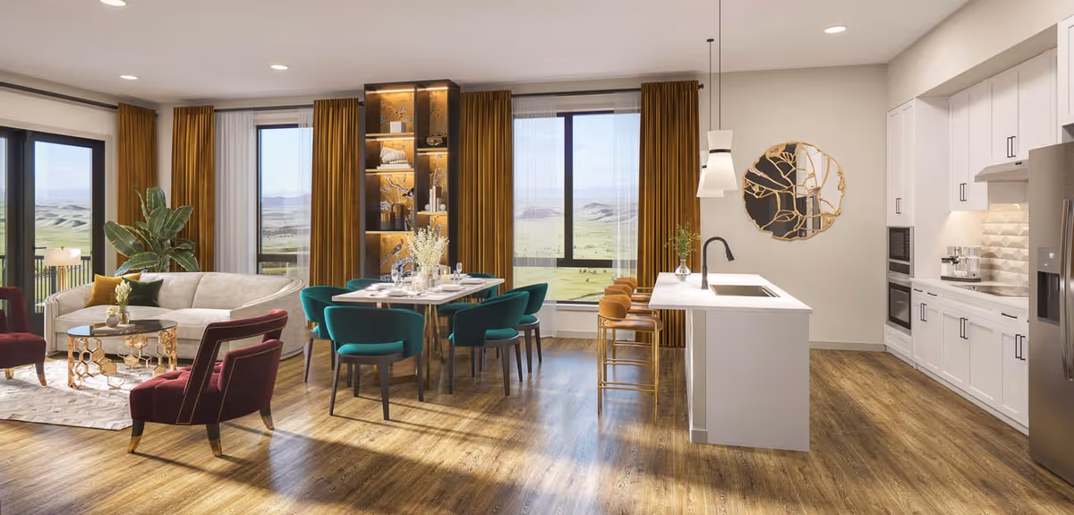 Bright open-concept living space featuring a modern kitchen with white cabinetry, a large island with three bar stools, and a dining area with a table set for six surrounded by teal chairs. Adjacent to the dining area is a cozy living room with a white sofa, two burgundy armchairs, a glass coffee table, and large windows with mustard-colored curtains offering a scenic view of rolling hills.