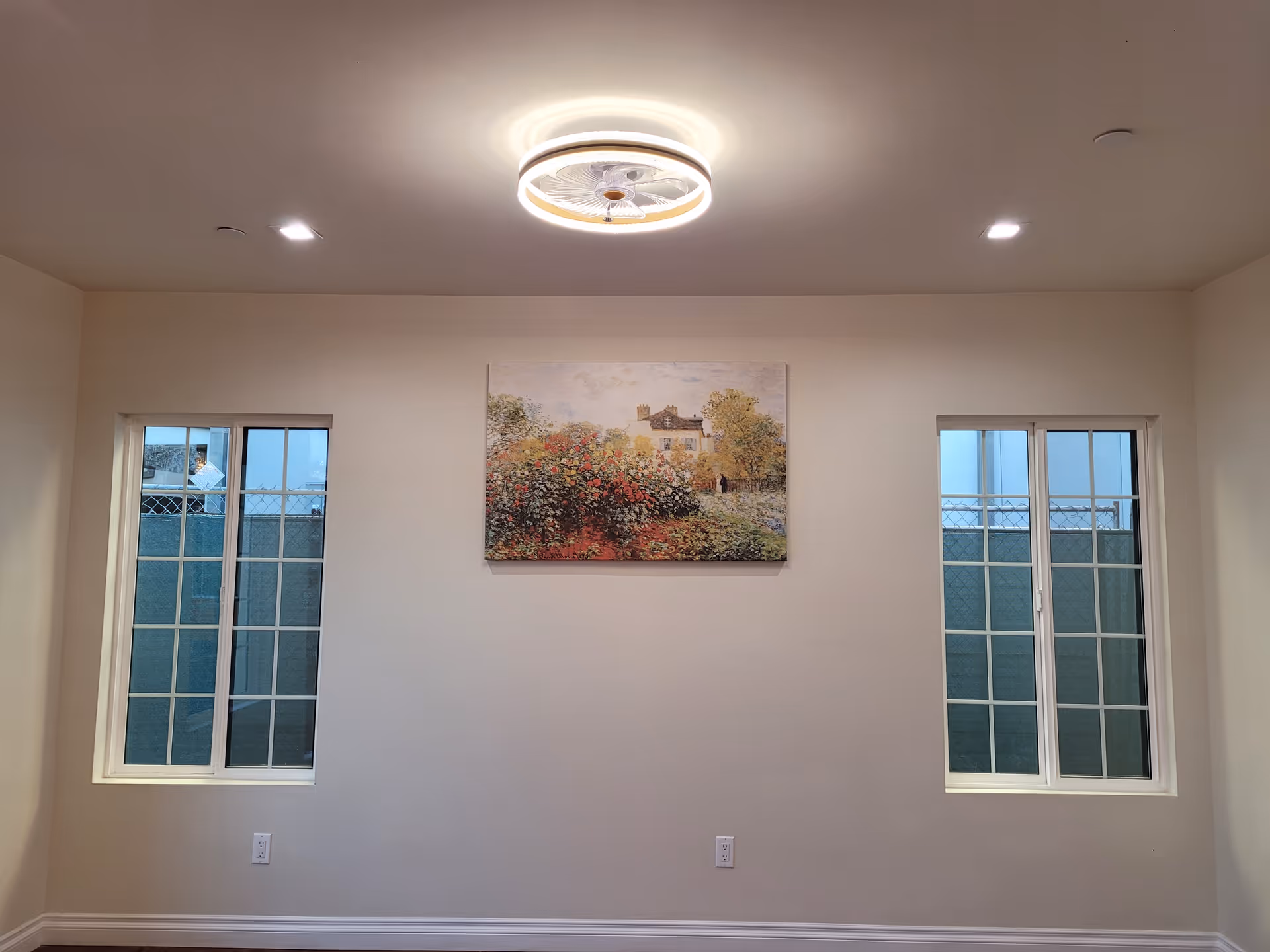 Interior wall with two windows, a landscape painting centered between them, and a ceiling light fixture.