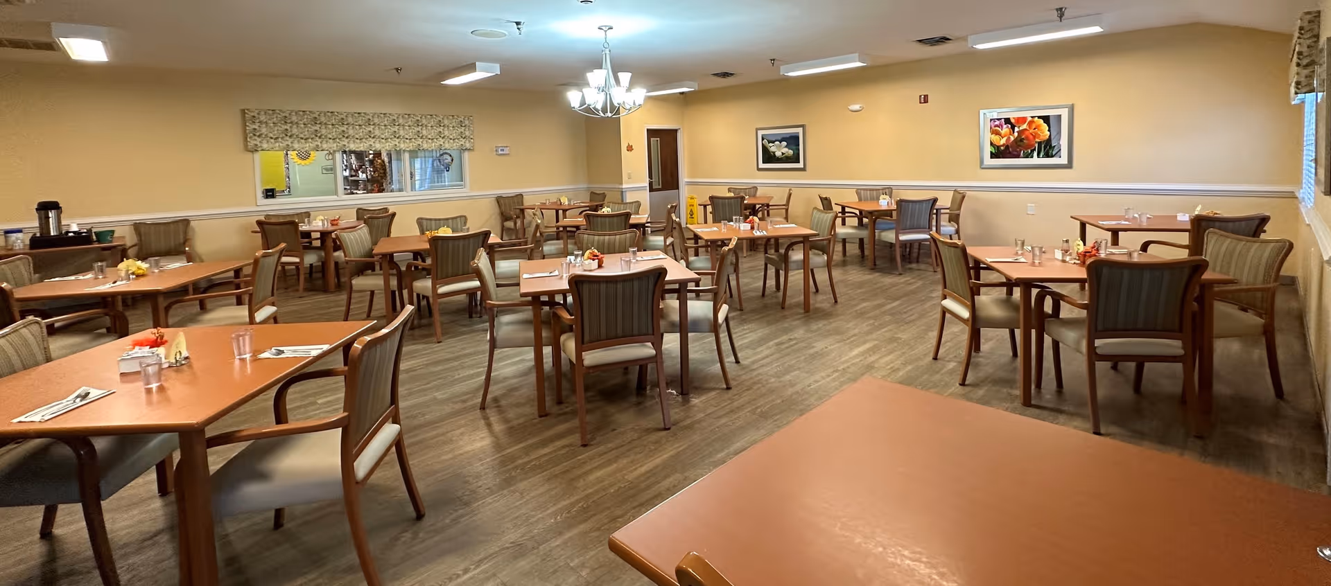 Spacious dining room with multiple wooden tables and chairs arranged for meals and soft wall decor.