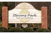 Wooden entrance sign reading "Stevens Park health and rehabilitation" mounted between two brick pillars with shrubs and the number 820 below.