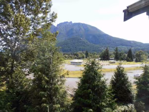 Mountain backdrop with trees and a parking lot seen from Red Oak Residence grounds.