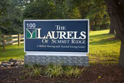 Blue sign for The Laurels of Summit Ridge on a stone pedestal amid landscaping.