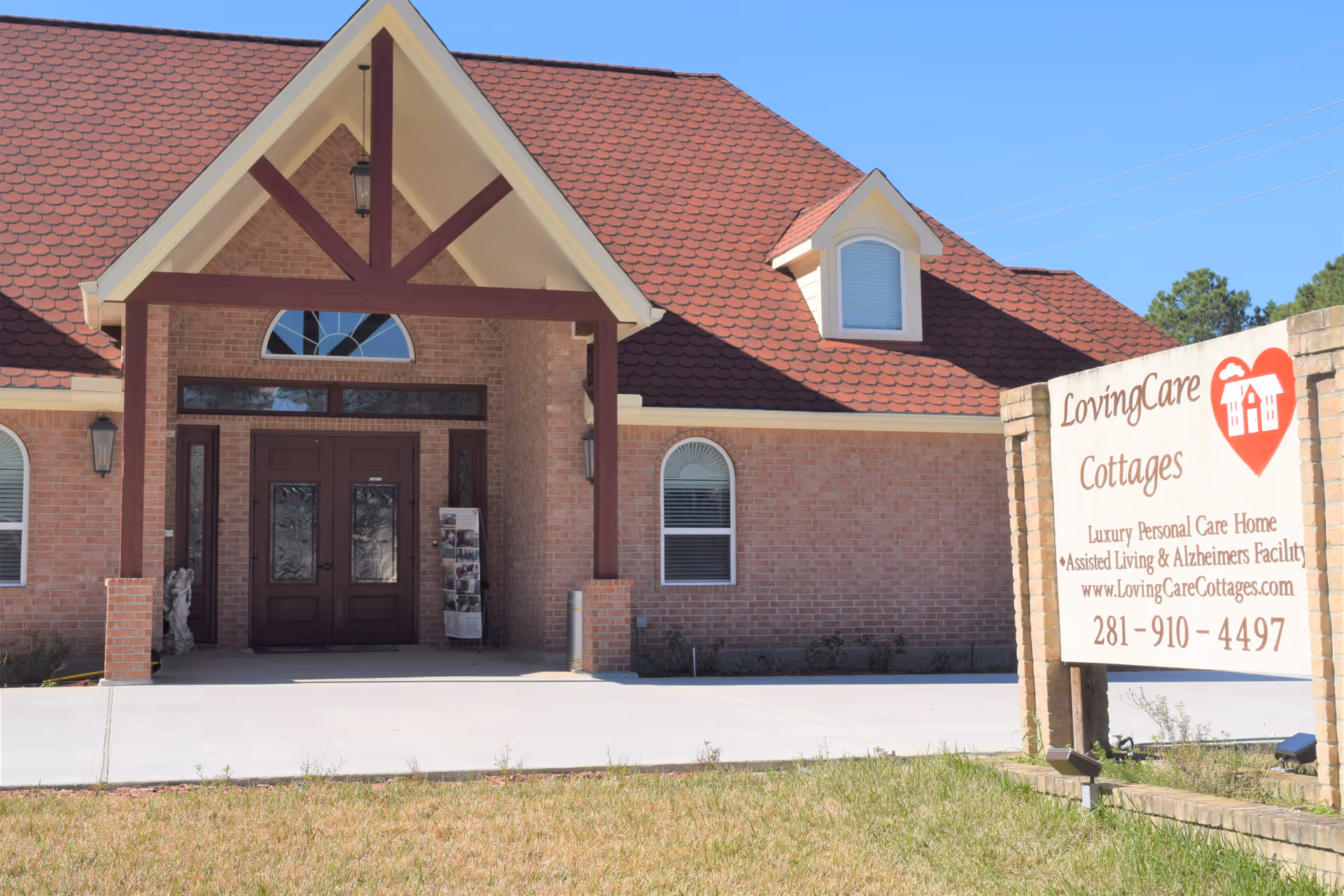 Front entrance of a brick assisted living building with a covered portico and a sign for LovingCare Cottages.