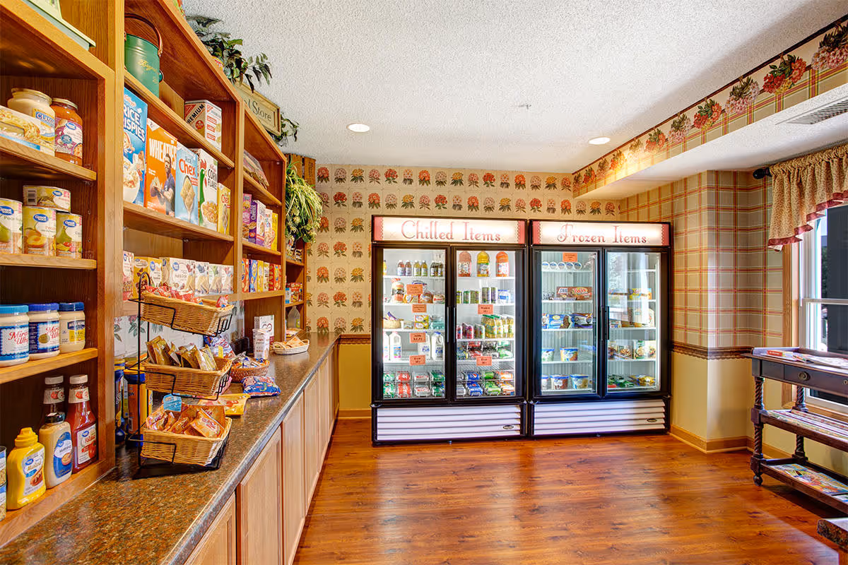 Small indoor market area with wooden shelves of snacks and three refrigerated cases labeled "Chilled Items" and "Frozen Items".