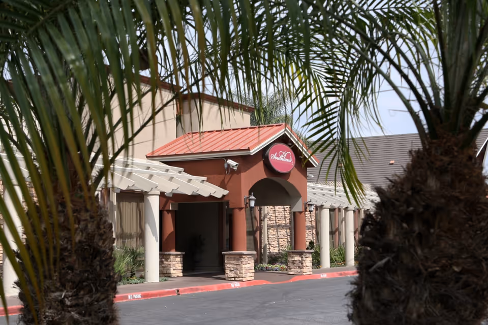 The front entrance of the Southland Care Center building framed by palm trees.