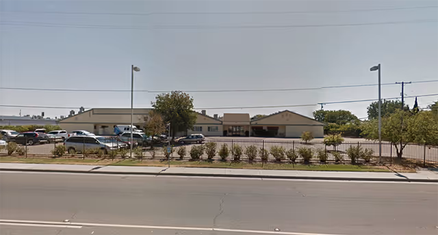 Exterior view of Golden Haven senior living facility with parking lot and fence.