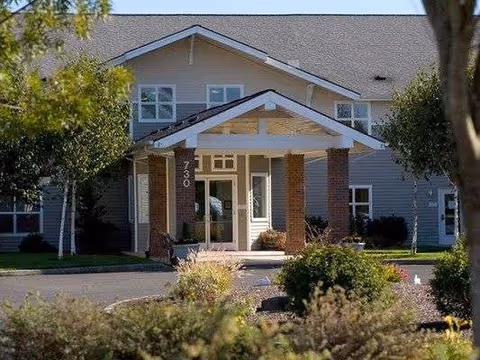 A senior living facility entrance with a covered portico and landscaped front garden.