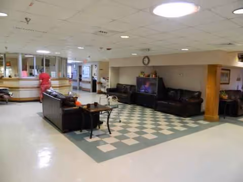 Lobby seating area with couches, tables, and reception desk in Kinder Retirement and Rehabilitation Center