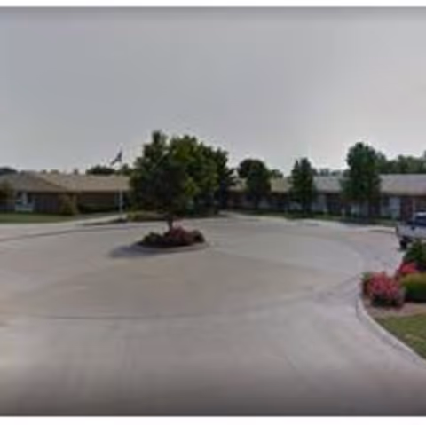 Circular driveway with a landscaped island in front of a single-story senior living building.