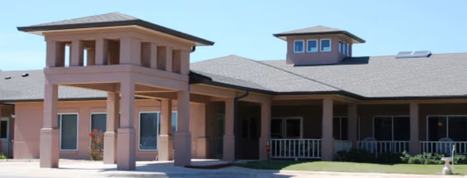 Front exterior of a single-story residential care building with a covered entrance supported by columns.
