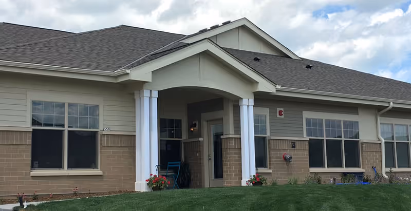 Front view of Village Pointe Commons entrance with columns and green lawn.