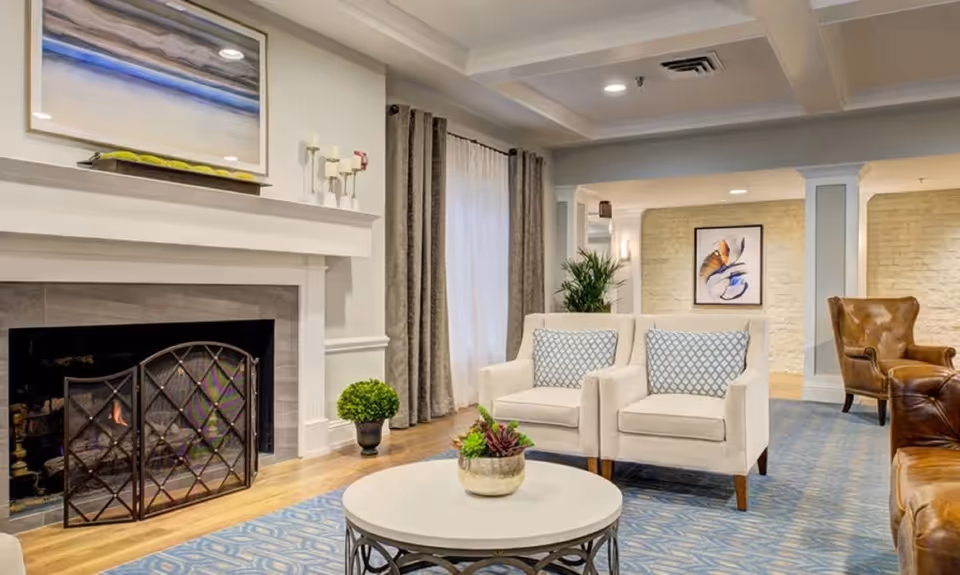 Bright furnished sitting room with a fireplace, two armchairs, coffee table and decorative accents.