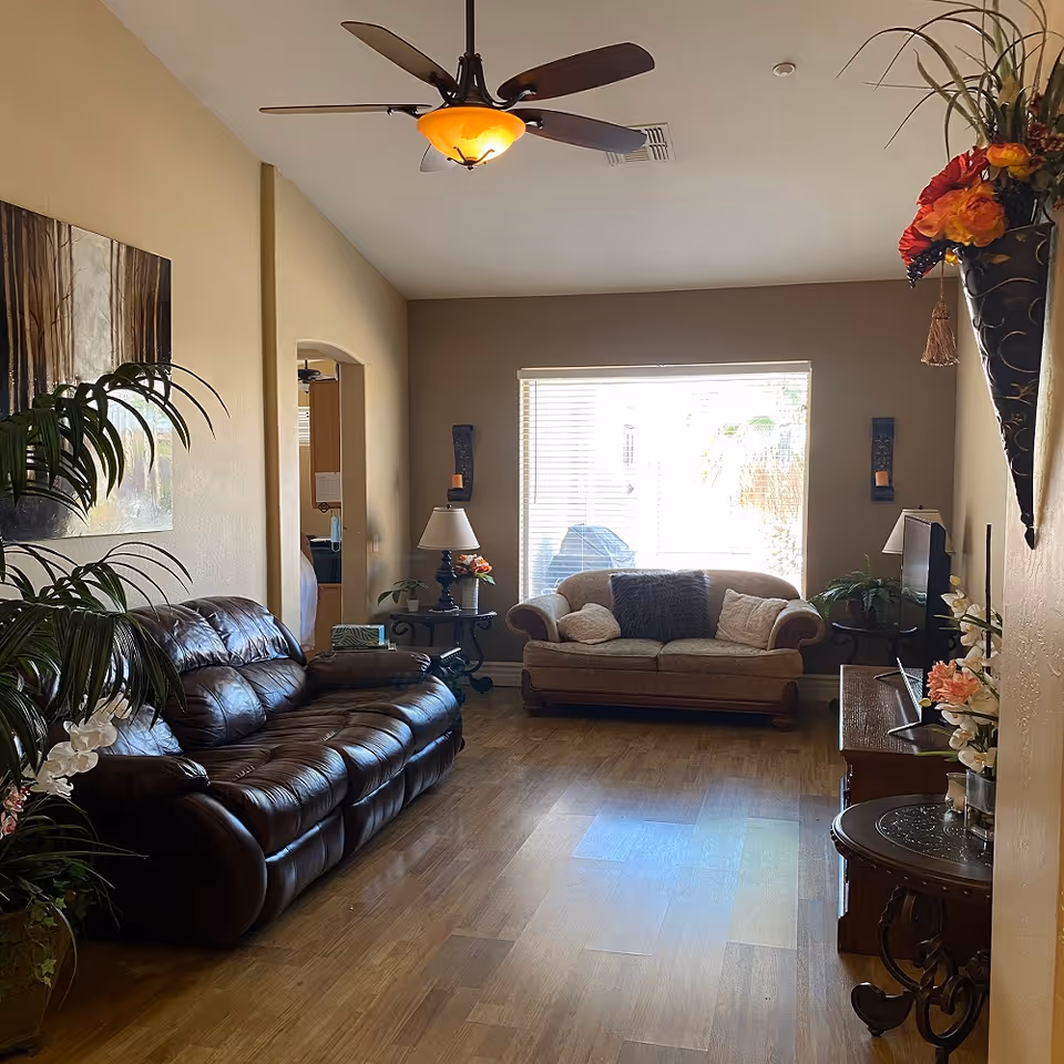 A cozy living room in a senior facility with leather sofas and natural light.