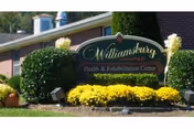 Williamsburg Health and Rehabilitation Center sign in front of brick building with yellow flowers.