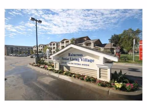 Entrance sign reads Raincross Senior Living Village with a building and landscaped area behind.