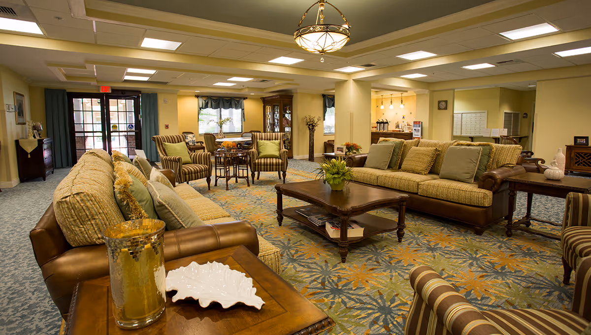 Spacious senior living lounge with sofas, armchairs, coffee tables, and decorative accents.