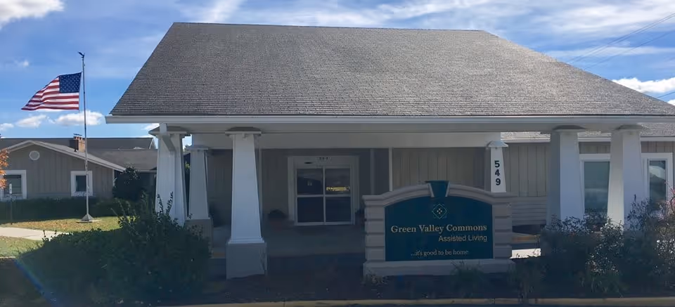 Front view of Green Valley Commons Assisted Living building with a flag outside.