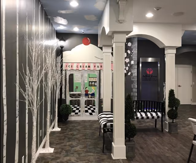 Indoor common area with white columns, striped benches and a mural of an ice cream parlor at the end of a hallway.