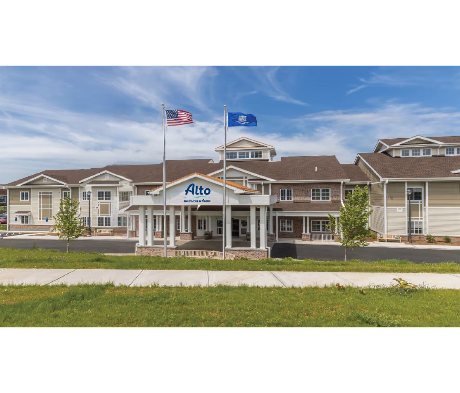 Front exterior of the Alto Evergreen Walk senior living building showing the entrance portico, two flagpoles, and signage.