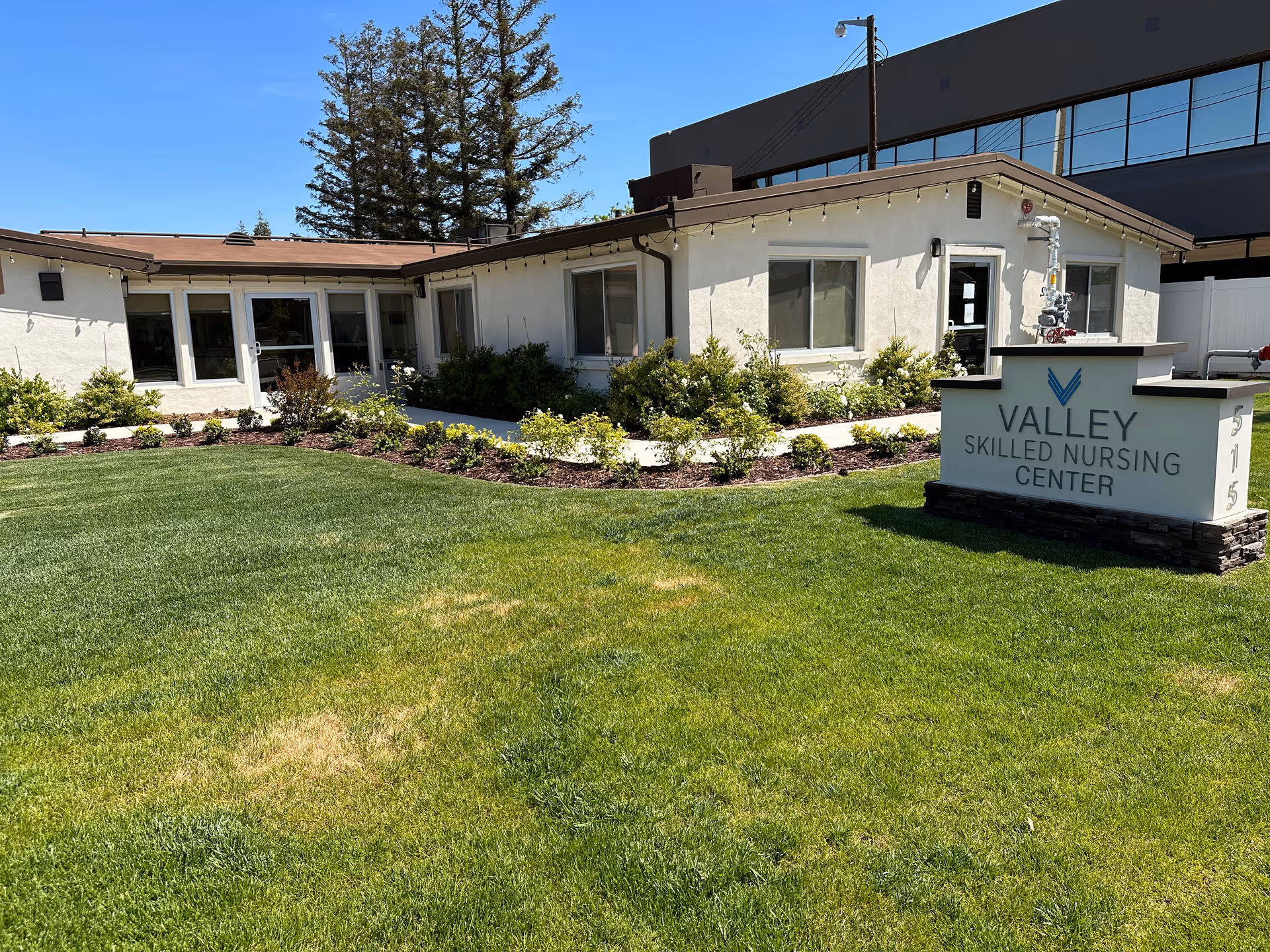 Front exterior of a single-story nursing facility with a manicured lawn and a sign reading 'Valley Skilled Nursing Center'.