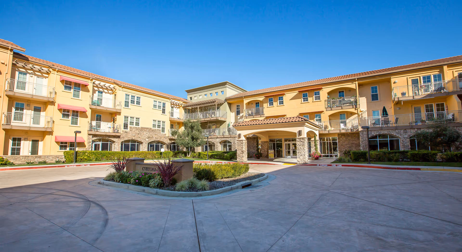 Sunlit exterior of Cogir Brentwood senior living facility with balconies and entrance.