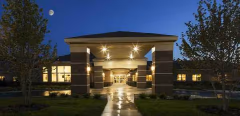 Evening exterior view of WellBridge of Brighton entrance with lit walkway and trees.