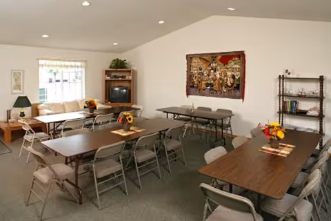 Interior common area with tables, chairs, a couch, and wall art.