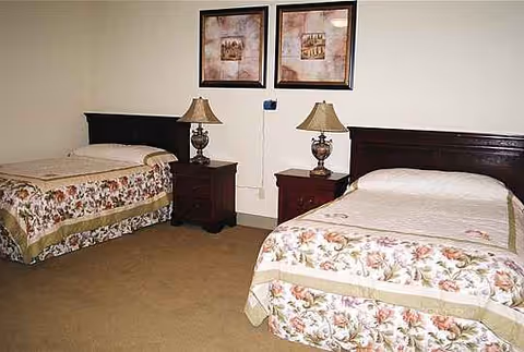 Two twin beds with floral bedspreads, nightstands, lamps, and framed art in a bedroom.