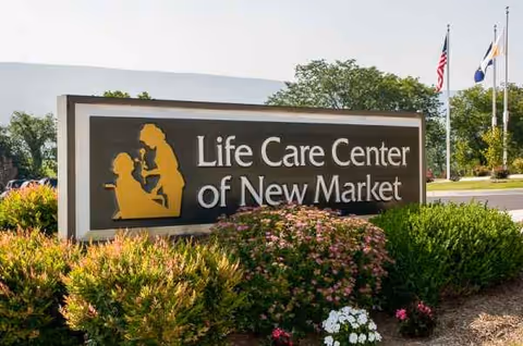 Exterior view of Life Care Center of New Market sign with shrubs and flags
