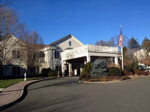 Exterior view of The Greens at Cannondale entrance with flag and landscaped surroundings.