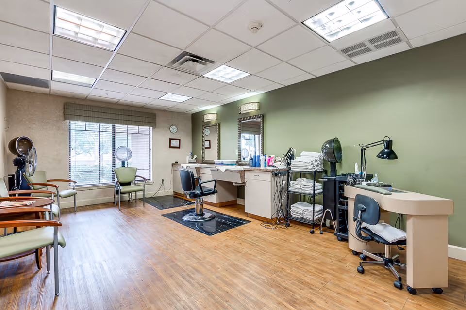 Interior salon area with styling chairs, mirrors, hair dryers, towels, and a manicure station.