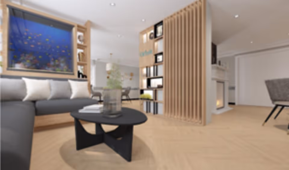 A modern living room with a gray sectional sofa adorned with white pillows, a black coffee table with a glass vase and books, wooden flooring, a decorative wooden partition with shelves, and a fireplace in the background.