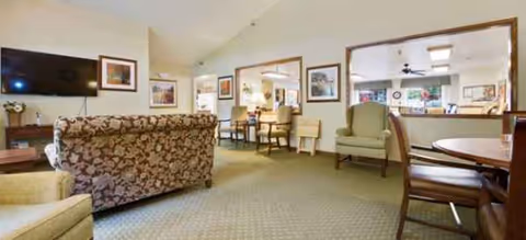 Spacious Brookdale Neenah lounge with couches, chairs, a TV, and wall-mounted art.