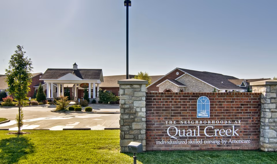 Exterior view of The Neighborhoods at Quail Creek senior living facility with a sign.