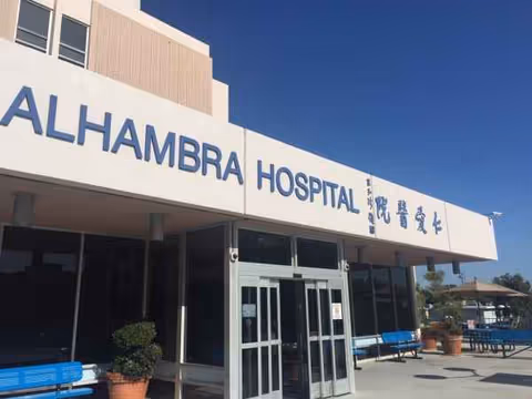 Exterior view of Alhambra Hospital Medical Center entrance with glass doors and benches.