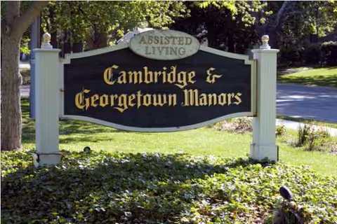Outdoor sign reads Cambridge and Georgetown Manors Assisted Living on a grassy front lawn.