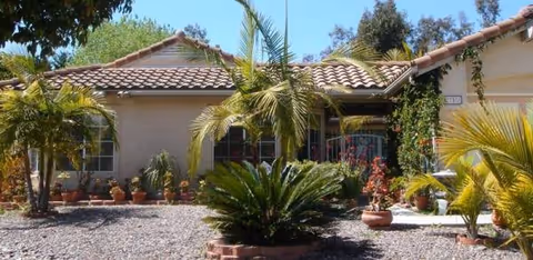 Exterior of a single-story building with a tiled roof and tropical landscaping.