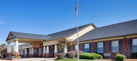 Bedford Estates Senior Living exterior: brick building with flagpole and covered entrance.