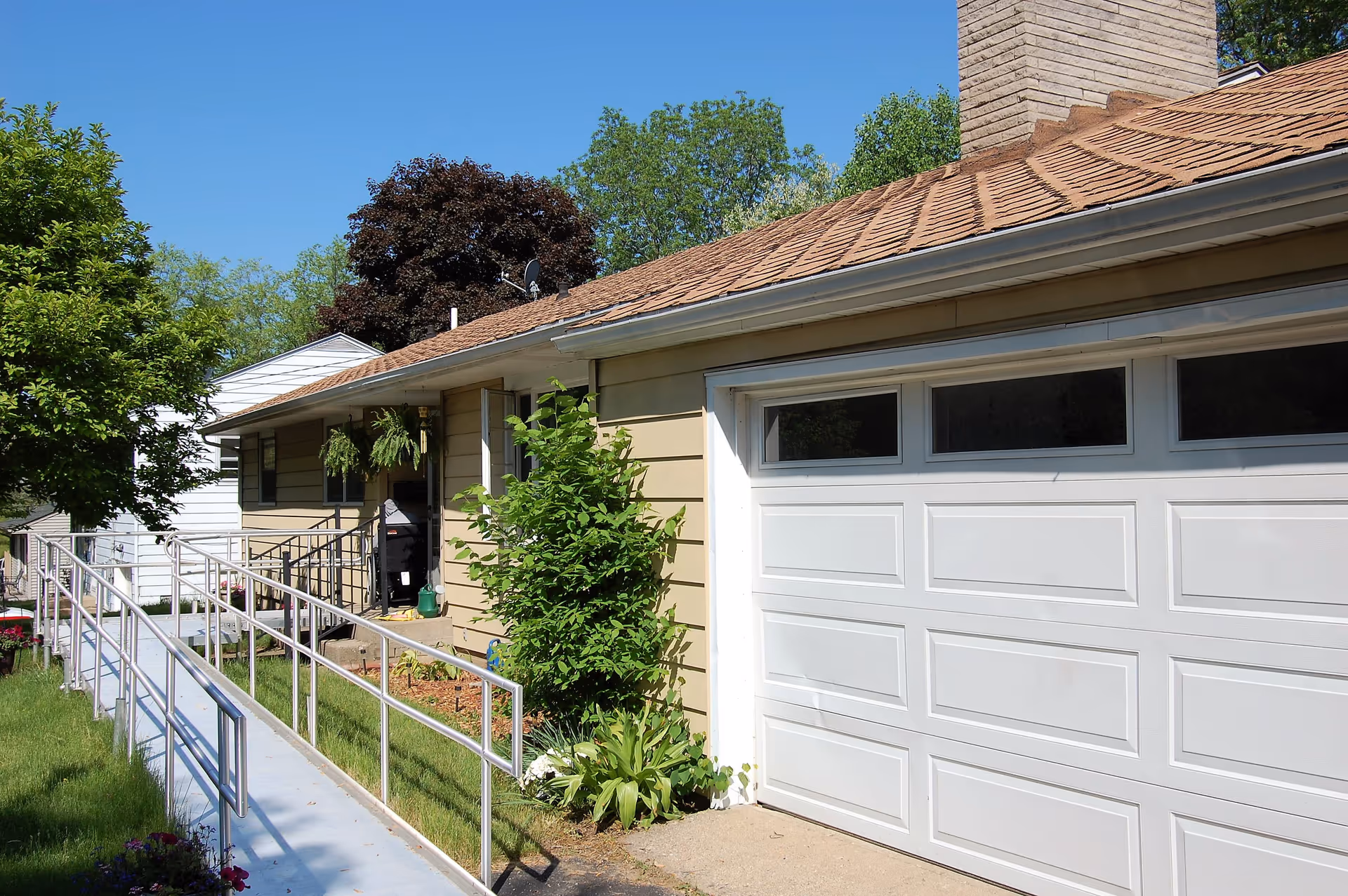 Single-story assisted living home exterior with a garage and an accessibility ramp to the front entrance.