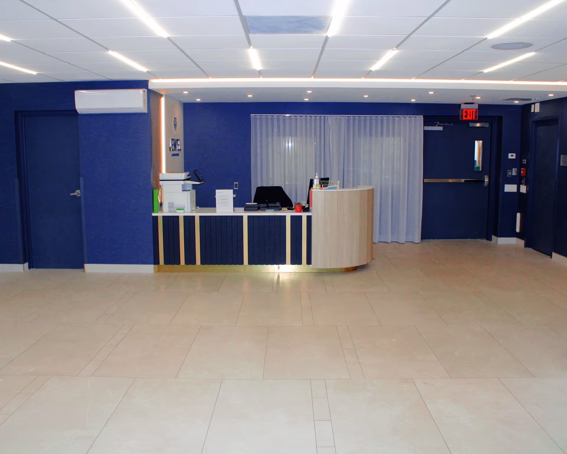 Reception desk and lobby area with a curved counter, blue walls, and a tiled floor.