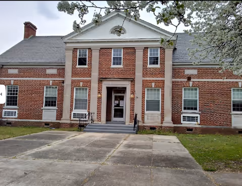 Brick senior living facility exterior with central entrance and steps.