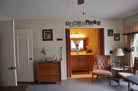 Living room scene with pink tufted chairs, a wooden dresser, and a doorway to the bathroom.