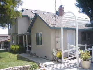 Exterior view of Abigail Board & Care LLC building with a white arched walkway.